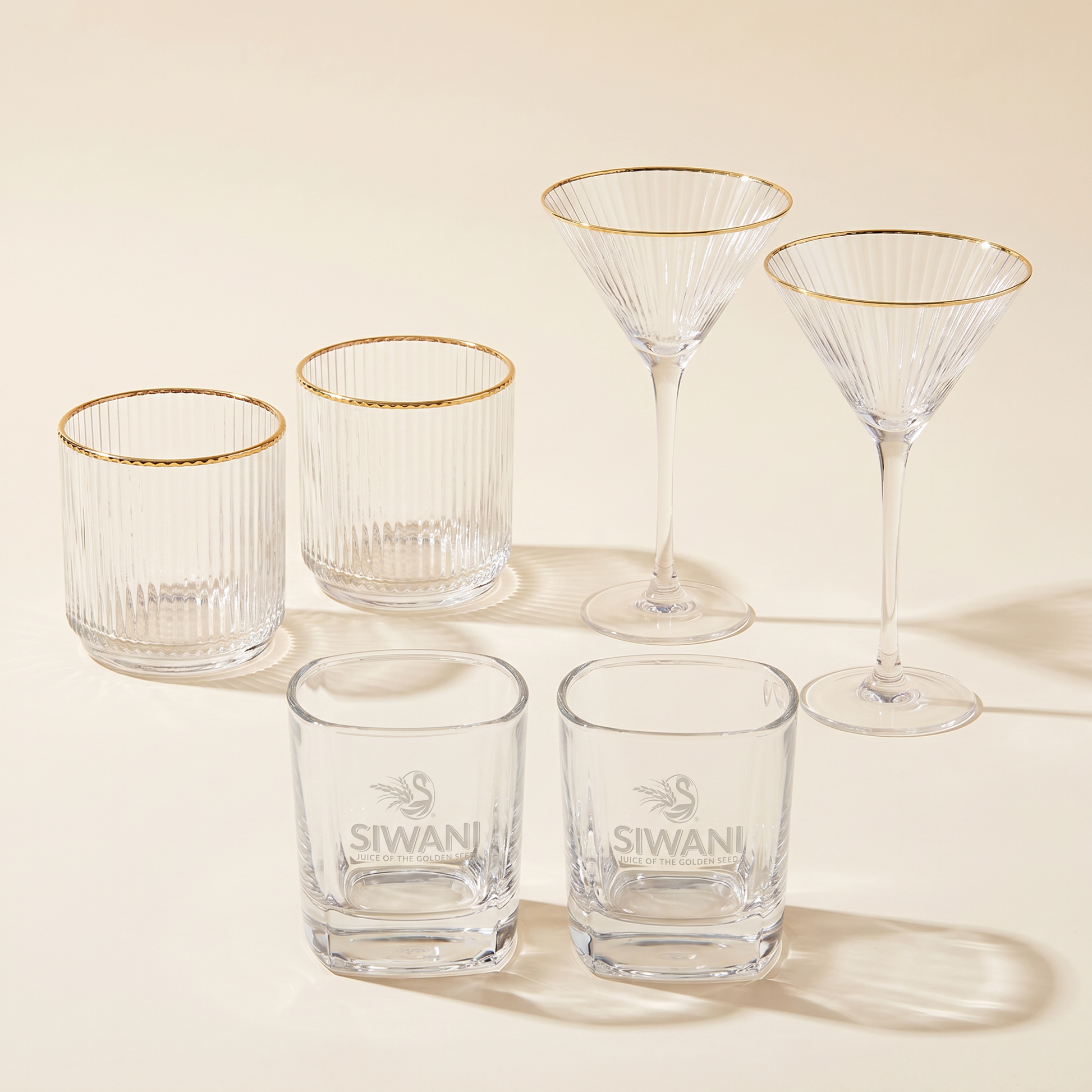 The Legacy Service — two gold-rimmed tumblers, two martini glasses, and two Siwani ball glasses studio composite
