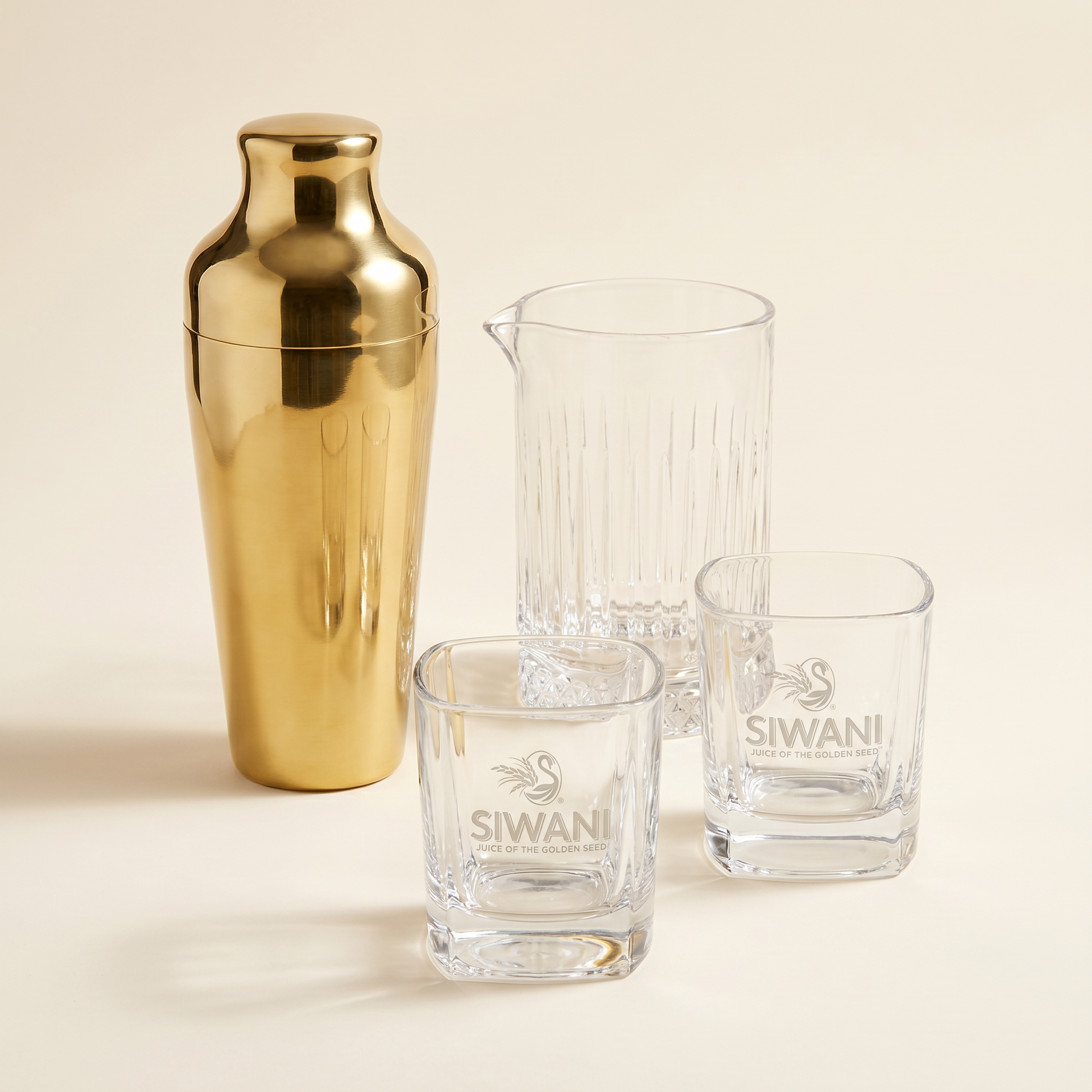 The Mixologist's Vanguard — gold cocktail shaker, crystal mixing glass, and two Siwani ball glasses studio composite